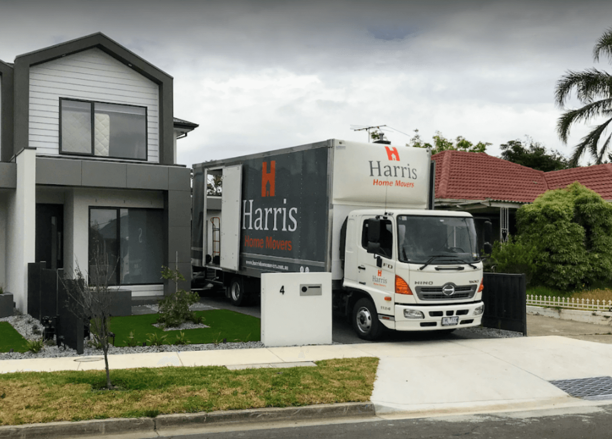 A Harris Movers truck parked next to a home for loading